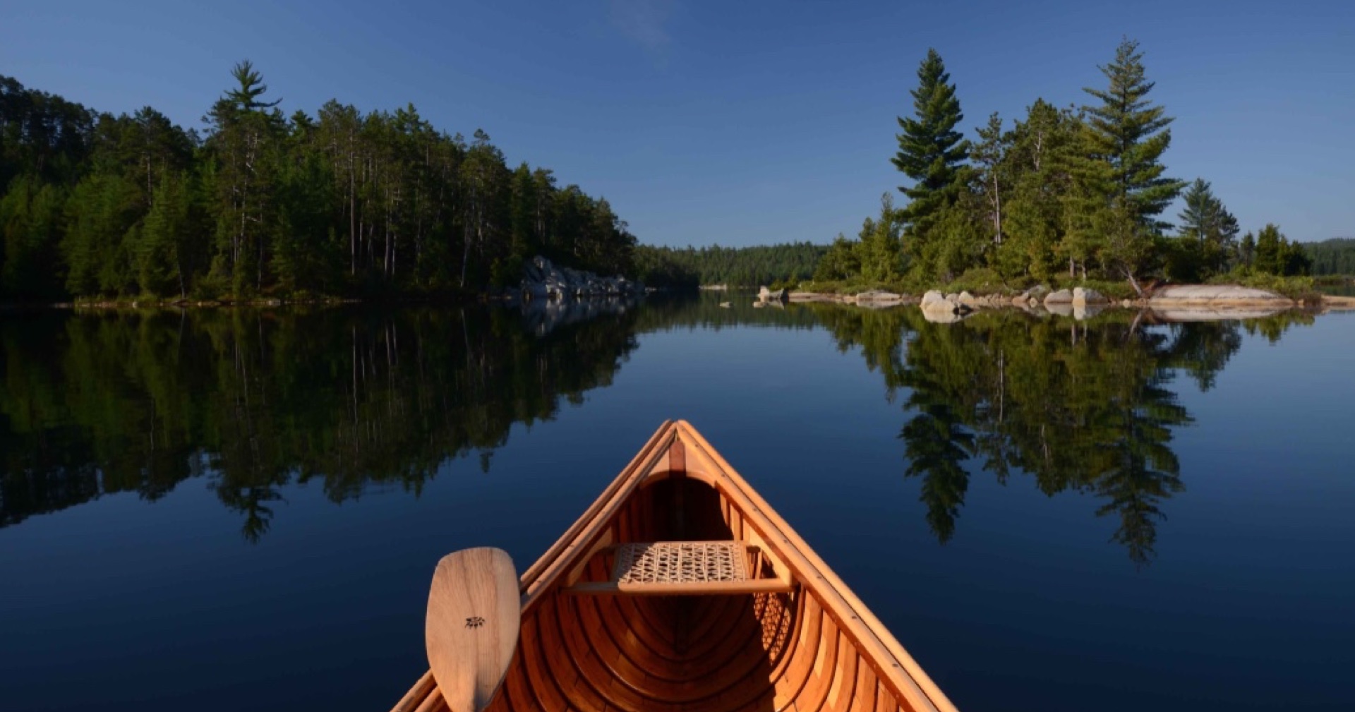 view of lake and forest wilderness from the bow of a canoe with a paddle
