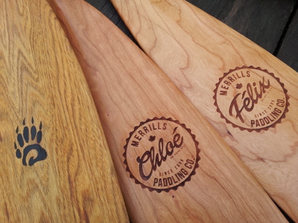 close up of 3 canoe paddles with custom designed laser engravings