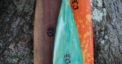 showing a teal, pink, and a walnut canoe paddles