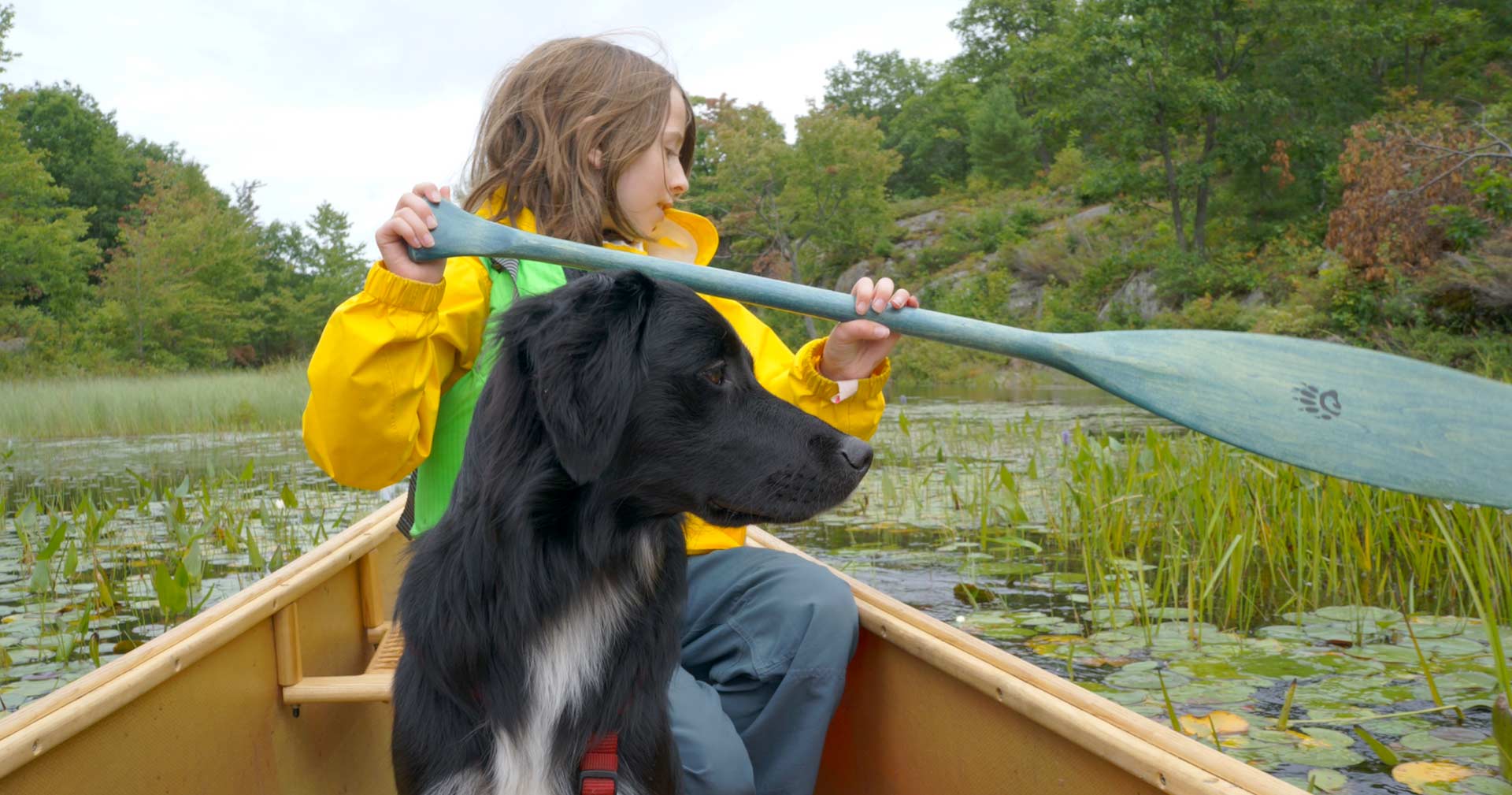 young girl paddling a canoe with her dog