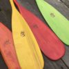 Colourful wooden kid paddles, showing tinted, stained, with red, orange, green, and yellow wooden paddle blades.