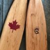 Detailed view of a Badger canoe paddle with an example of a MEDIUM custom laser engraved image of a maple leaf, filled red