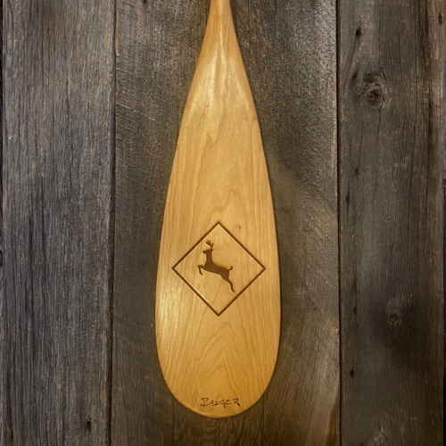 View of a Cherry La Bonga canoe paddle blade with laser engraved deer crossing sign motif on a barn board background