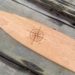 detail of a laser engraved nautical compass on a cherry wood canoe paddle