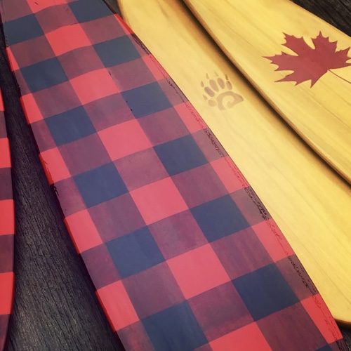 Showing detail on the blades of hand painted Buffalo Plaid and other custom (maple leaf) Canoe Paddles