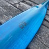 Detail of a vibrant blue tinted canoe paddle blade on a barn board background