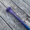 Detail of a purple tinted canoe paddle grip and shaft - on a barn board background.