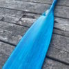 Detail of a vibrant blue tinted canoe paddle blade on a barn board background