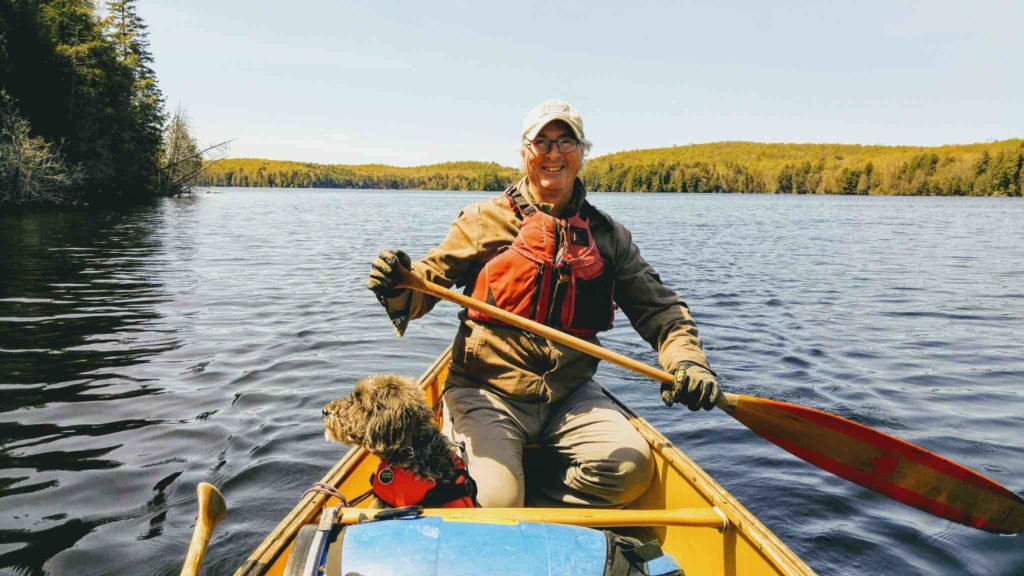 Kevin Callan and Oliver (the dog) in the stern, paddling a canoe on a Canadian Lake